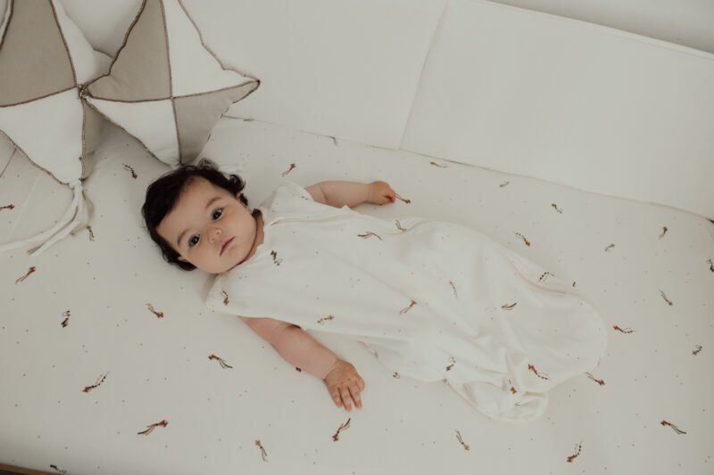 Bebé acostado con saco pijama de verano 0-6 meses con estampado de cometas, en algodón orgánico de Sonpetit Barcelona.