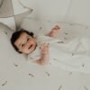 Bebé acostado sonriendo con saco pijama de verano 0-6 meses con estampado de cometas en algodón orgánico de Sonpetit Barcelona.