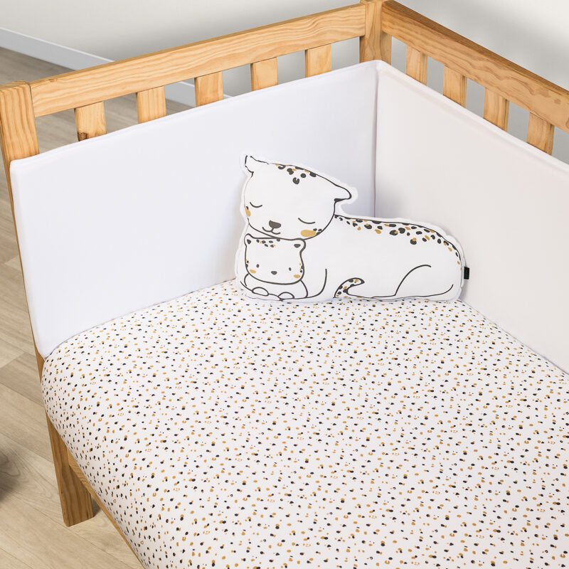 Funda nórdica color beige con estampado de motas y cojín de leopardo sobre cuna de madera. Sonpetit Barcelona.